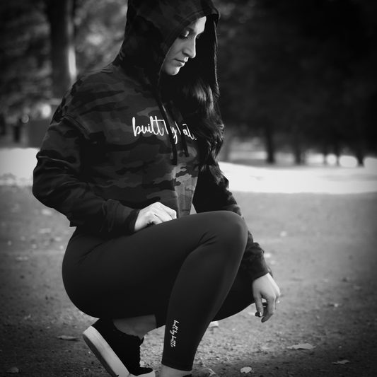 Woman crouched down in park wearing Built By Battle leggings and cropped hoodie